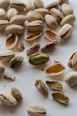 Peeled and whole pistachio nuts arranged together on clean white backdrop.
