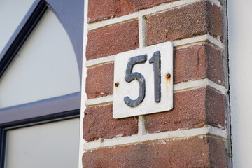 House number sign 51 next to front door, exterior facade detail with modern home entrance and address plate.