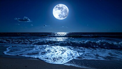 Full moon shining brightly over a dark ocean with waves gently washing onto a sandy beach at night.