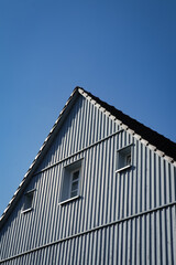 House with pointy roof, windows and chimney, against a clear blue sky.