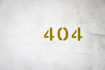 Golden number 404 painted on an old weathered concrete wall, showing metallic house number detail.