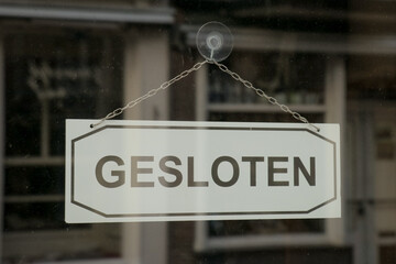 Closed sign on white glass door. Window store entrance, gesloten means closed in Dutch, Netherlands. 