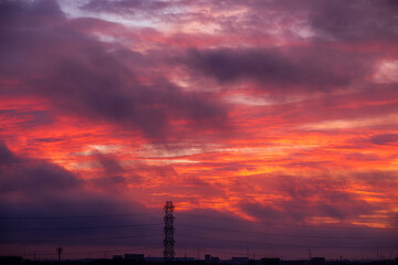 真夏の夜明けにたなびくあかね雲と鉄塔
