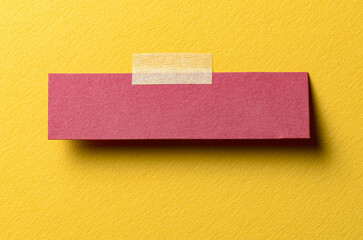 Piece of blank red paper note with adhesive sticky tape and shadow on yellow background