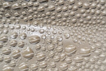 This macro photograph captures a fascinating pattern of water droplets forming on a smooth surface.