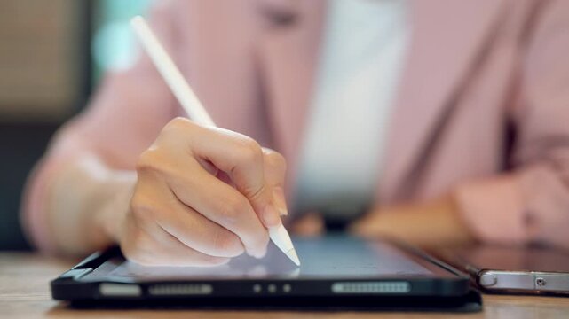 Woman freelancer using digital pen to draw or write on tablet device, creative work concept in casual outfit
