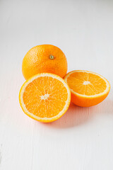 Halved orange fruit on white wooden background
