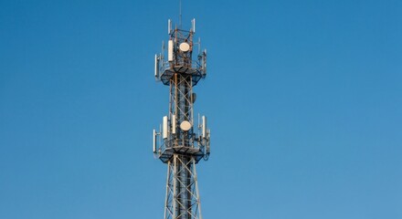 Tall metal telecommunications tower against a clear blue sky.  Multiple antennas and dishes are mounted