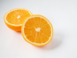 Halved orange fruit on white wooden background, close-up
