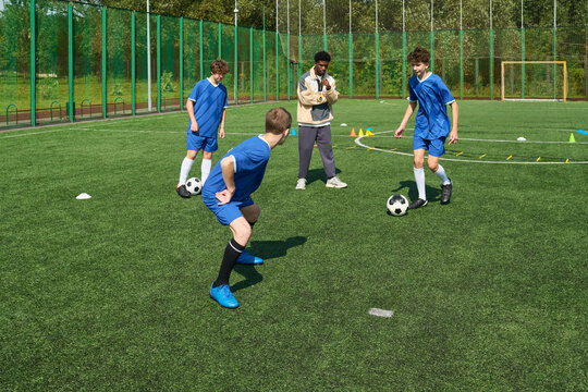Group of teenage boys practicing soccer drills on outdoor field while Black man coach observing and instructing, soccer balls and training cones scattered on artificial turf - Powered by Adobe