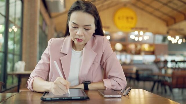 Close-up of businesswoman checking time and planning tasks on tablet using stylus and smartwatch in office environment