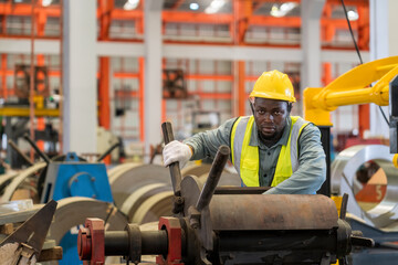 A Man is focused working on a machine in a factory. Staff is inspecting the operation of machinery in a factory.