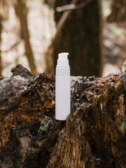 A dark and light glass serum bottle with a dropper, tree bark wood, moss. forest on a sunny day nature background. Concept of skin care, hydration, cosmetic demonstration eco-friendly product mock up