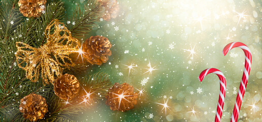 Christmas background with decorative branch, golden bow, candy canes and cones for tree decoraton. New Year winter holidays concept with decor in green and gold colors and copy space, top view.