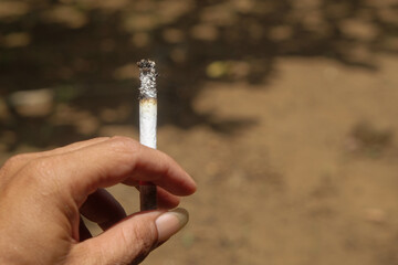 Close up of a hand holding a kretek cigarette. For graphic design, 3D rendering and banners