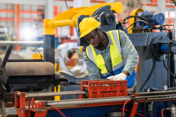 A Man is focused working on a machine in a factory. Young man engineer working hard in factory.