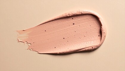 Fototapeta premium Close-up of a light peach-colored cosmetic product smear on a beige background.
