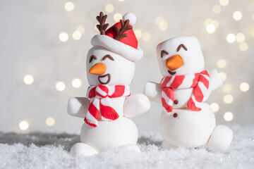 Obraz premium Two marshmallow snowmen with red scarves and hats