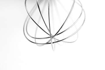 Abstract stainless steel whisk isolated on white. High-resolution photo of a stainless steel whisk tool with artistic placement on a white background. Perfect for cooking and design visuals.
