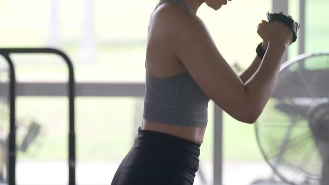 Woman in gym doing fitness workout, wearing gloves and sweating. Illustrates strength, energy, and committed lifestyle.
