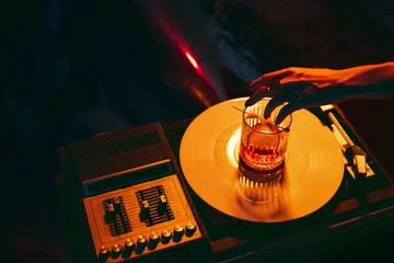 Fototapete Bar Hand adjusting cocktail glass on vinyl turntable in moody nightlife atmosphere. Concept of entertainment marketing, bar culture, lifestyle advertising, and creative event visuals.  © master1305