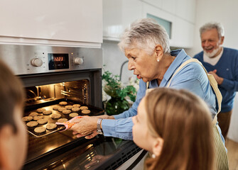 Portrait of grandparents and grandchildren having fun together preparing and eating baked dessert food in kitchen at home