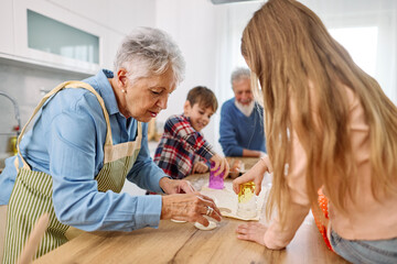 Portrait of grandparents and grandchildren having fun together preparing dough food in kitchen at home