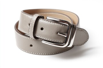 A coiled grey leather belt with a prominent silver buckle sits on a white surface casting a soft shadow