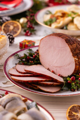 Classic Christmas food medley on a decorated table. Fish, dumplings stuffed with cabbage and mushrooms, cheesecake, and ham.