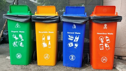 Four color-coded waste bins for organic, recyclable, general, and hazardous waste, promoting effective waste management and recycling practices.