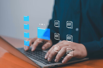 Businessman managing digital files and folders on laptop with virtual interface, symbolizing cloud storage, data management, organization, and modern technology solutions management with