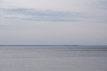 A tranquil lake under a cloudy sky with soft ripples and a distant horizon. Minimalist nature scene evoking calm, solitude, and introspection
