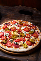 Pizza with salami, jalapeno pepper, cherry tomatoes and mozzarella cheese. Soft focus.	