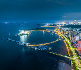 Naklejka premium Aerial view of the illuminated coastal cityscape and modern architecture by the bay at night in Zhuhai.
