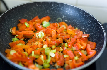 Close Up of a Vegetarian Fried Red Orange Bell Pepper with Spring Onion and Savory Herb in a Pan, Healthy Diet