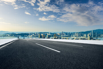 Fototapeta premium Empty asphalt road with a modern city skyline and sea view.