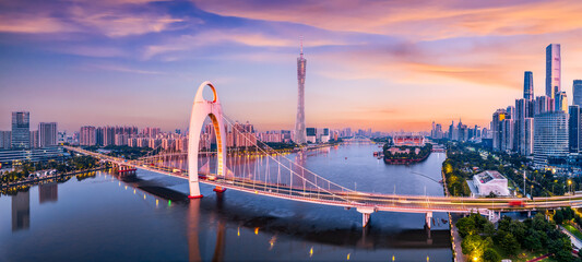 Modern bridge and city financial district skyline under a colorful sunset sky in Guangzhou. © zhao dongfang