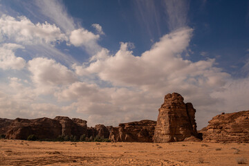 Monoliths and desert sand against dramatic clouds in the desert near Al Ula in Saudi Arabia