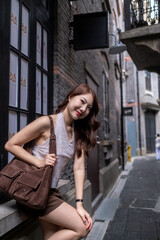 A woman is sitting on a ledge with a brown purse on her lap. travel concept.