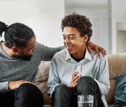Portrait of a happy teenage boy son talking to his father at home. Sharing secrets and having fun, support and parenthood concept