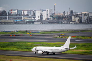 Airplane jet landing on runway on taxi lane in airport and aircraft traffic to landing with industrail factory background