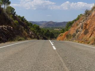 Downhill road heads towards mountains in the background