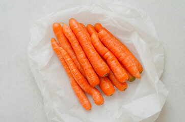 Fresh young carrots top view on light stone countertop