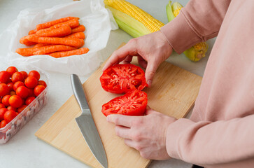 Man slicing juicy beefsteak tomato on wooden board
