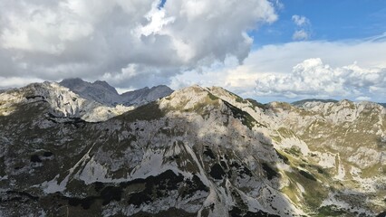 A breathtaking view from a high mountain peak with rugged rocks under a dramatic sky filled with textured clouds. Perfect for nature lovers and adventure-themed projects.
