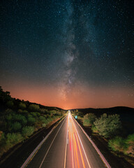 Estrada com rastos de luz e c&eacute;u com estrelas