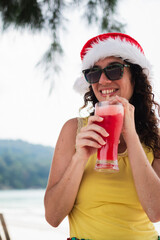 Woman enjoying tropical christmas beach vacation drinking cocktail
