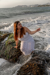Plus-size white Colombian Latina girl posing on a rock at sunset. Concept of Latinos, tourism, vacation, nature, and Latin America. High quality photo
