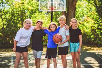 teens in sportswear playing basketball game outside together