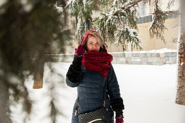 Walking photoshoot in the snowy city of a pretty young girl dressed in a blue jacket, jeans and a...